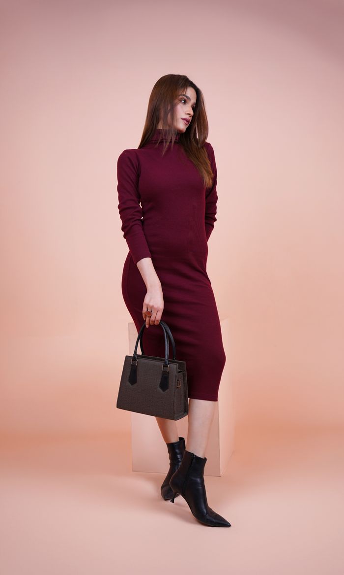 creative Fashion model in a burgundy dress, posing with a handbag and boots in a studio setting.