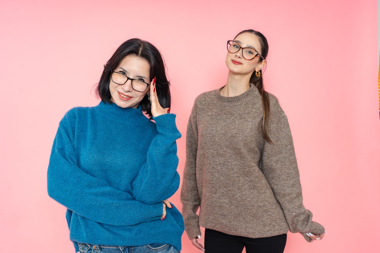 Services-01 Two women in stylish sweaters posing against a pink background.