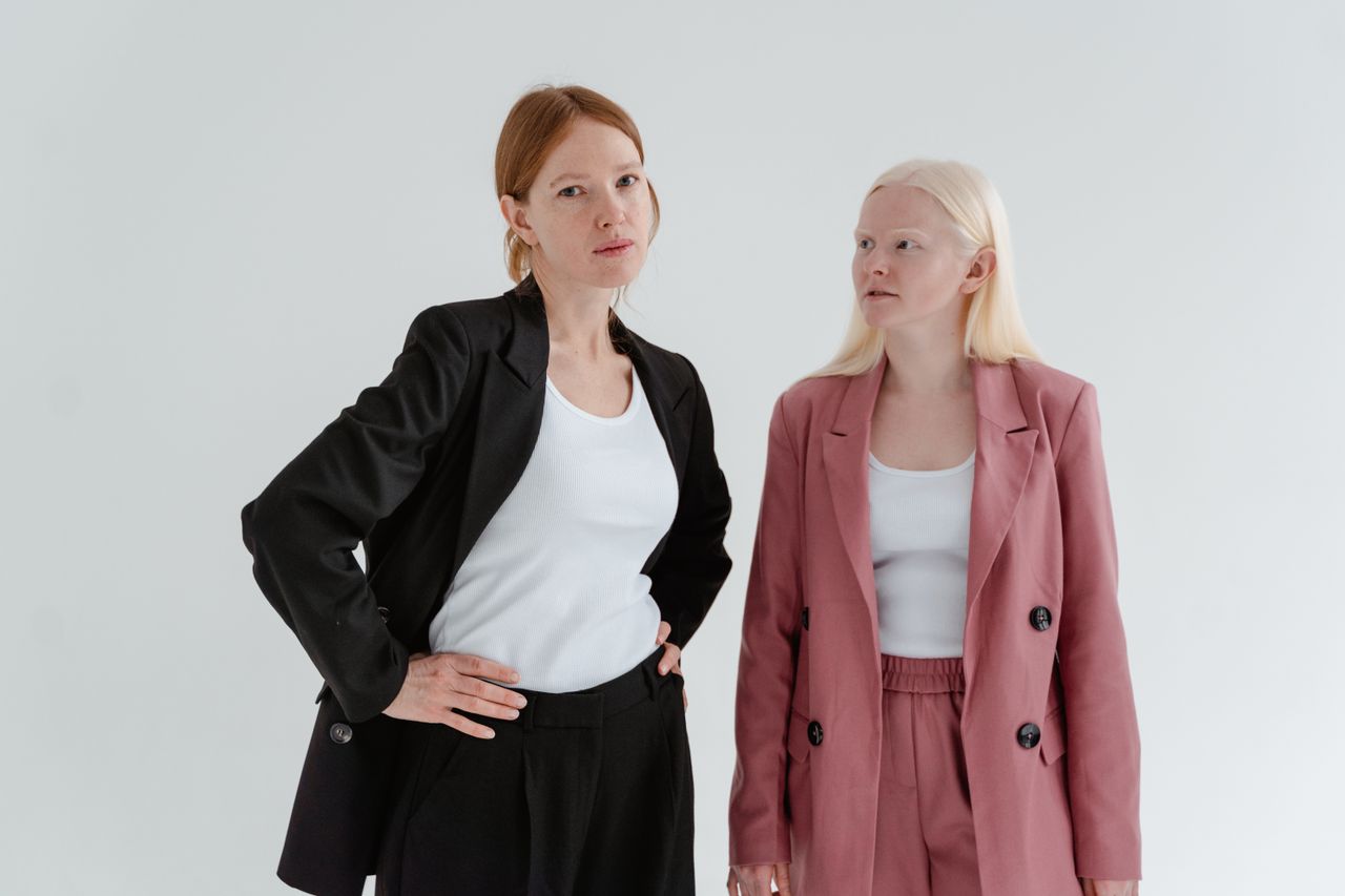 why-choose-us Two women in business suits exuding confidence on a white studio background.